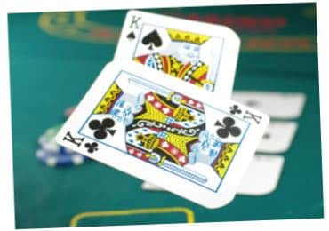 Två spelkort, spader kung och klöver kung, som virvlar i luften ovanför ett pokerbord i casinot