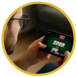 En man sitter med mobilen i händerna och spelar poker på mobilen. Bilden ska illustrera en person som spelar poker hos en svensk pokersida