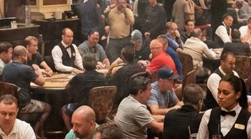 Pokerturnering på ett casino. vid Rummet är fullt av pokerbord med spelare. I bilden syns också delers och casino-personal.