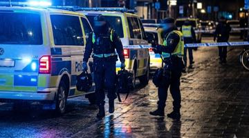 Bild på polisbussar med blåljus, avspärrningsband och poliser. Bilden ska illustrera en polisinsats i stadsmiljö.