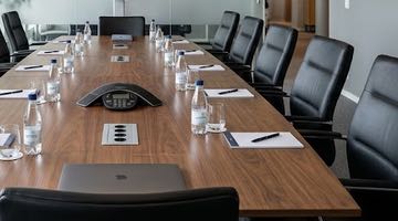 Ett konferensbord som förberetts för möte. Vid varje plats finns en flaska vatten, vattenglas, block och penna. Bilden ska illustrera att Finansdepartementet bjudit in till ett möte med Pokerförbundet.